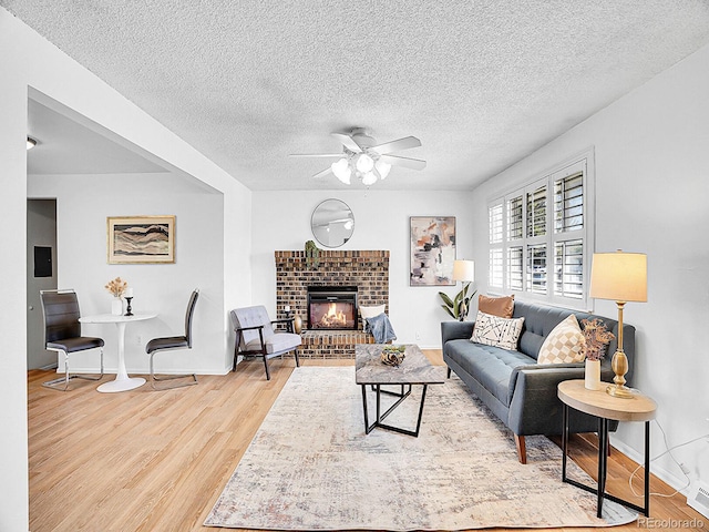 5225 Beech St, Arvada, CO 80002 - living room featuring ceiling fan, wood finished floors, a fireplace, baseboards, and a textured ceiling
