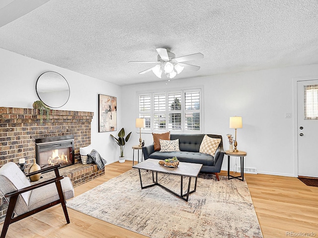 5225 Beech St, Arvada, CO 80002 - living area with ceiling fan, plenty of natural light, wood finished floors, a brick fireplace, and a textured ceiling