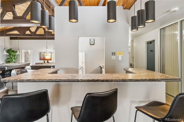 kitchen with freestanding refrigerator, a towering ceiling, a kitchen breakfast bar, and pool table