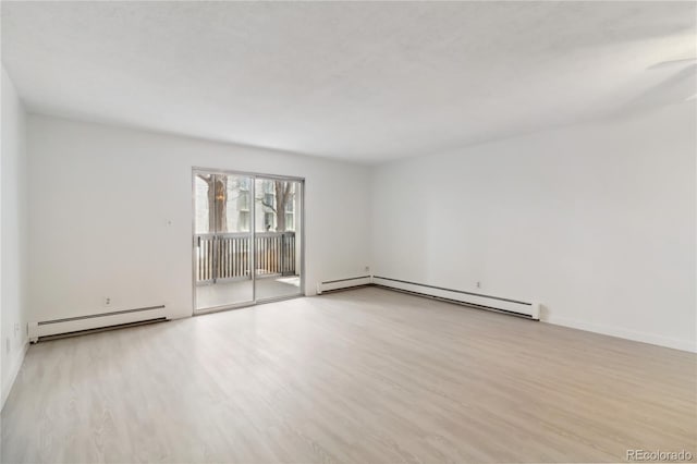empty room featuring wood finished floors, baseboards, and a baseboard heating unit