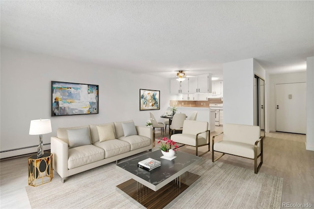 living area with a textured ceiling, a baseboard radiator, ceiling fan, and light wood-style floors