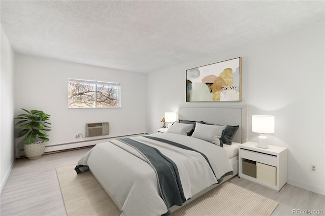 bedroom featuring baseboards, an AC wall unit, light wood finished floors, and a textured ceiling