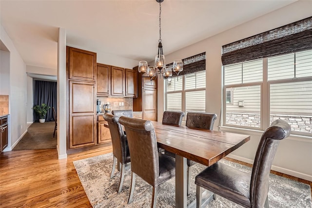 dining area with light hardwood / wood-style flooring and a chandelier