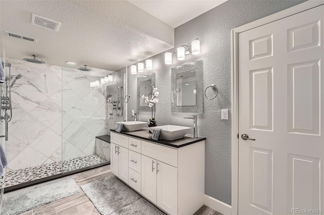 bathroom featuring vanity, a shower with door, and a textured ceiling