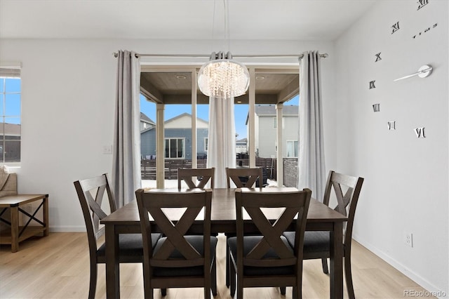 dining space with an inviting chandelier, a wealth of natural light, and light hardwood / wood-style flooring