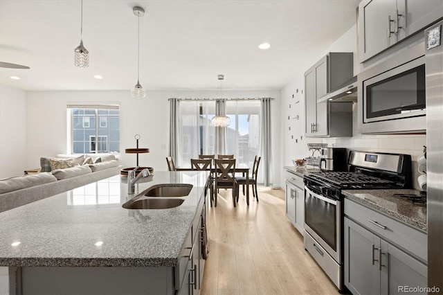 kitchen with a kitchen island with sink, decorative light fixtures, and appliances with stainless steel finishes