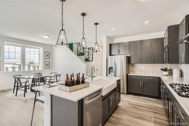 kitchen featuring a sink, stainless steel appliances, light wood-style flooring, and decorative backsplash