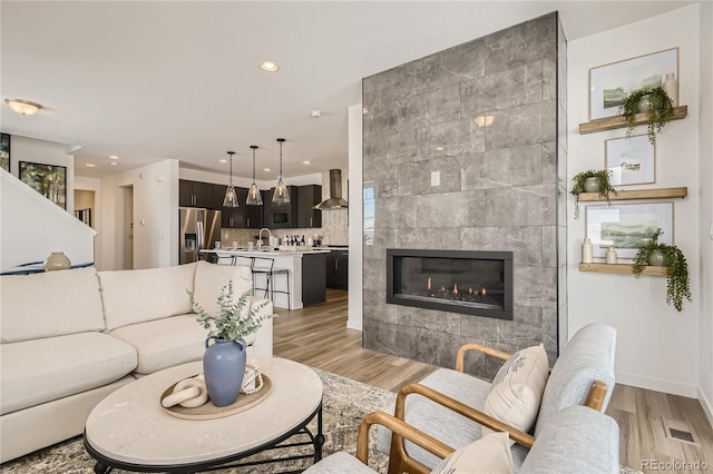 living room featuring recessed lighting, visible vents, light wood-style flooring, and a tile fireplace