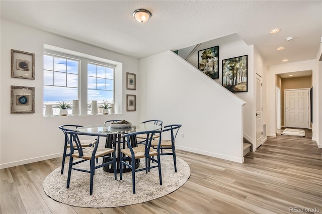 dining room featuring stairs, light wood-style flooring, recessed lighting, and baseboards