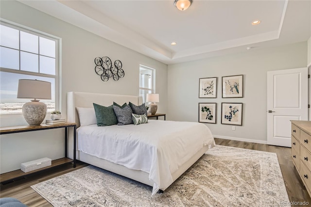 bedroom with visible vents, baseboards, a tray ceiling, recessed lighting, and wood finished floors