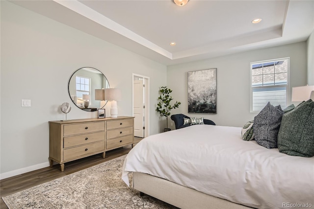 bedroom with recessed lighting, baseboards, a raised ceiling, and dark wood-style floors