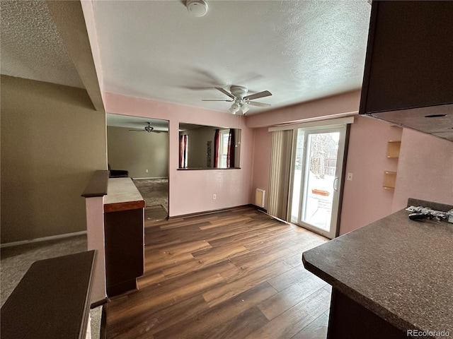 unfurnished living room featuring hardwood / wood-style flooring, ceiling fan, and a textured ceiling