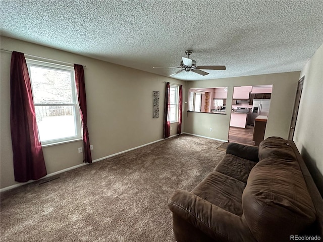 unfurnished living room featuring carpet flooring, ceiling fan, and a textured ceiling