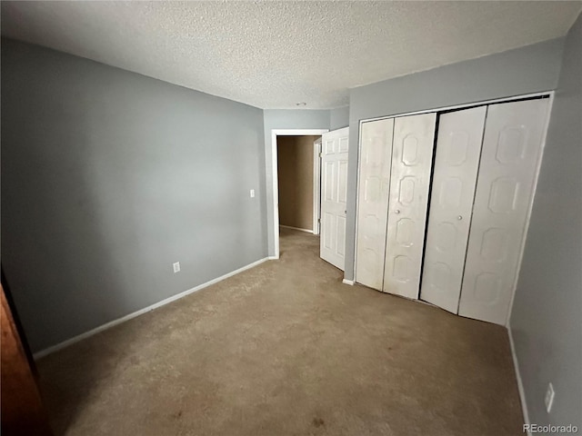 unfurnished bedroom with light colored carpet, a textured ceiling, and a closet