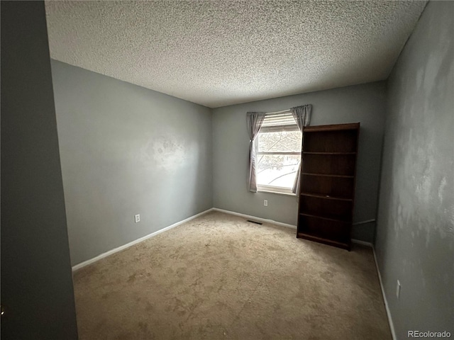 carpeted spare room featuring a textured ceiling