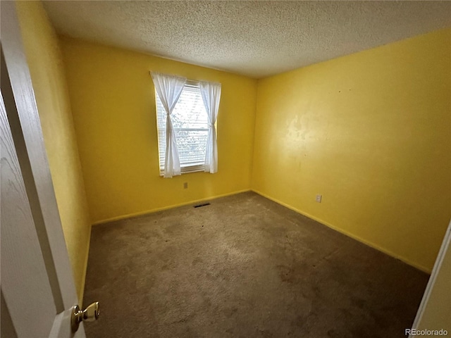 carpeted empty room with a textured ceiling