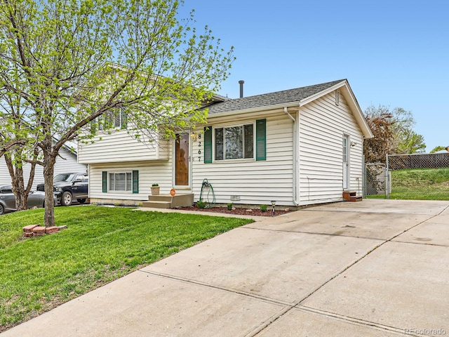 tri-level home with fence, concrete driveway, and a front yard