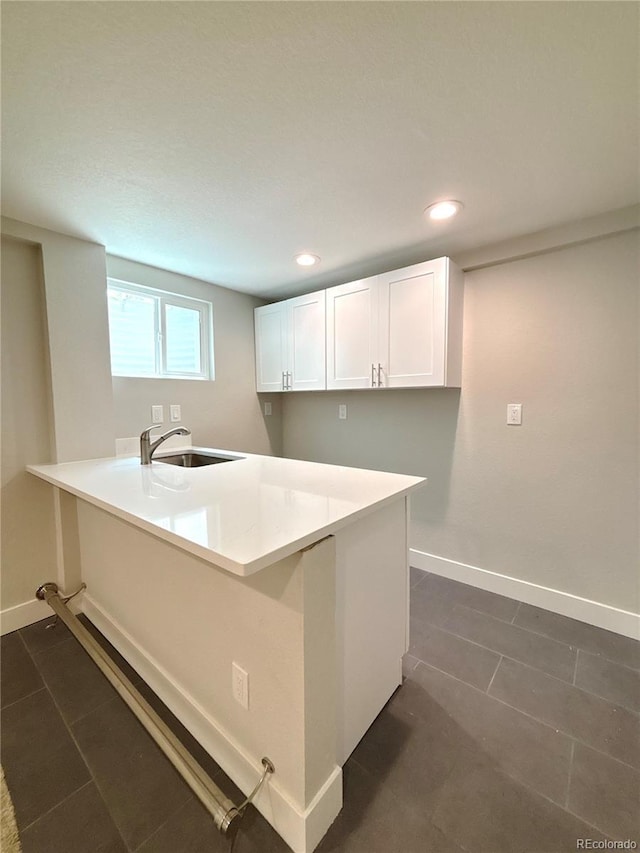 7160 E Iliff Ave, Denver, CO 80224 - kitchen with a peninsula, white cabinetry, dark tile patterned floors, recessed lighting, and light countertops