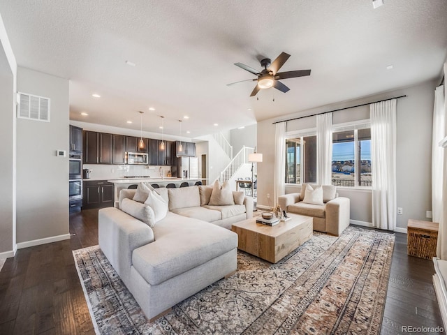 living room featuring ceiling fan, dark hardwood / wood-style floors, and a textured ceiling