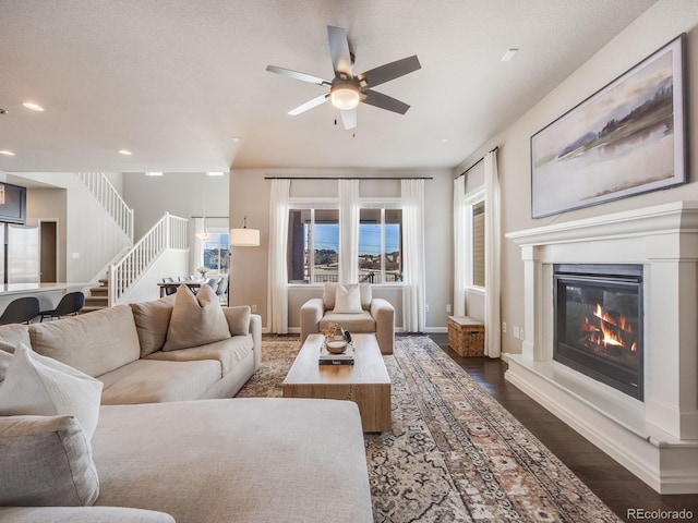 living room featuring ceiling fan, dark hardwood / wood-style floors, and a textured ceiling