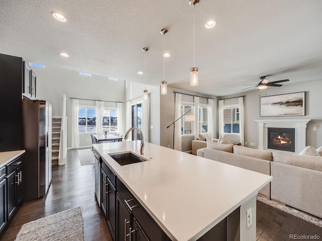 kitchen with sink, appliances with stainless steel finishes, hanging light fixtures, a center island with sink, and dark hardwood / wood-style flooring