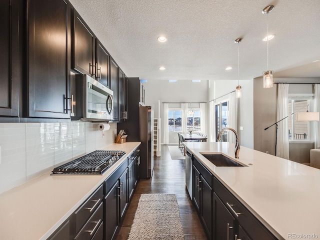 kitchen featuring sink, appliances with stainless steel finishes, dark hardwood / wood-style floors, tasteful backsplash, and decorative light fixtures