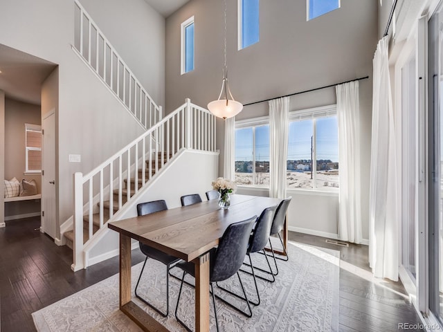 dining room with a towering ceiling and dark hardwood / wood-style flooring