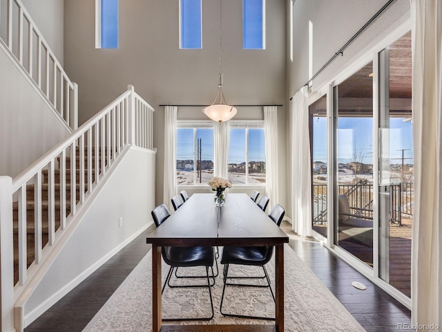 dining space featuring dark wood-type flooring and a high ceiling