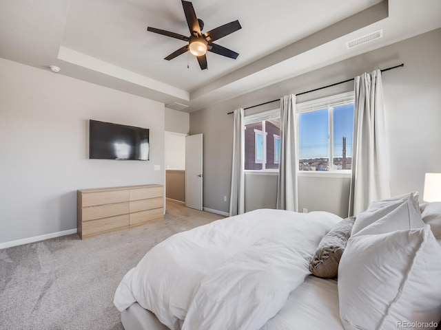 bedroom featuring light carpet, a tray ceiling, and ceiling fan