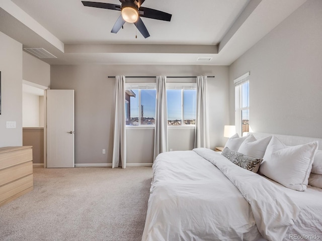 bedroom with a raised ceiling, light carpet, and ceiling fan