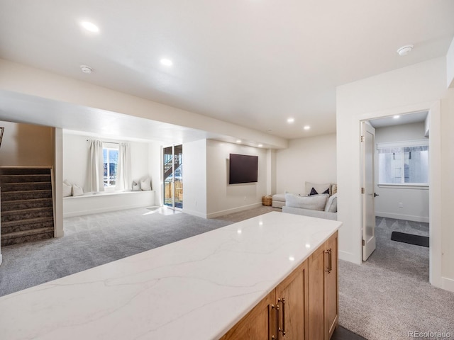 kitchen featuring light stone countertops and light carpet