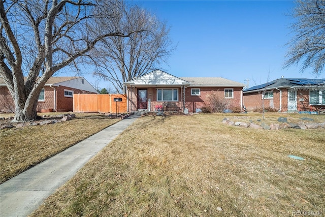 view of front of house featuring fence, a front lawn, and brick siding