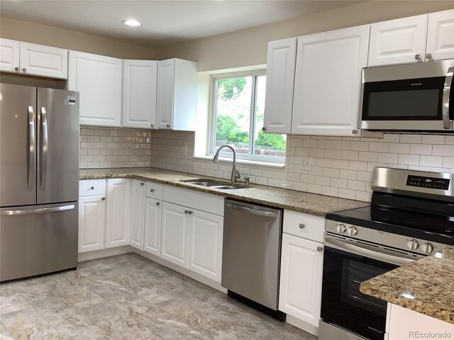 1152 S Eaton St, Lakewood, CO 80232 - kitchen featuring stainless steel appliances, a sink, white cabinets, light stone counters, and recessed lighting
