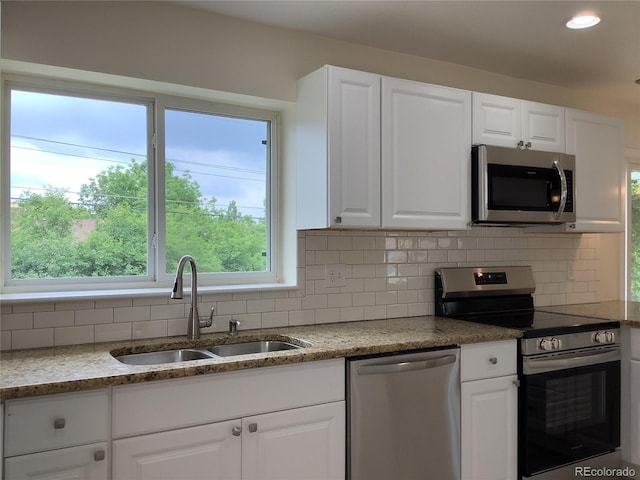 1152 S Eaton St, Lakewood, CO 80232 - kitchen with stainless steel appliances, a sink, white cabinets, decorative backsplash, and recessed lighting