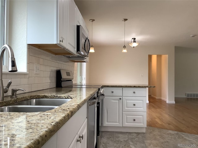 1152 S Eaton St, Lakewood, CO 80232 - kitchen featuring stainless steel appliances, a sink, a peninsula, tasteful backsplash, and white cabinetry