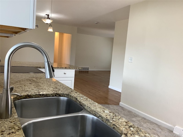 1152 S Eaton St, Lakewood, CO 80232 - kitchen view of a sink, white cabinetry, light stone counters, baseboards, and pendant lighting