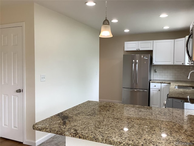 1152 S Eaton St, Lakewood, CO 80232 - kitchen with freestanding refrigerator, stone counters, backsplash, white cabinetry, and recessed lighting