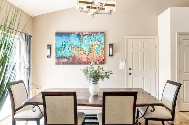 dining area with vaulted ceiling, hardwood / wood-style floors, and an inviting chandelier