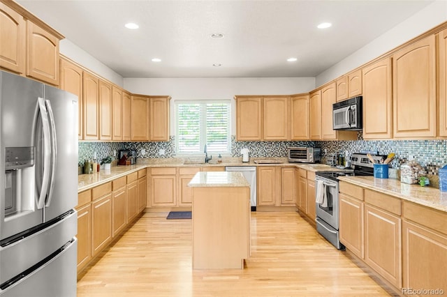 kitchen featuring sink, light hardwood / wood-style flooring, appliances with stainless steel finishes, a center island, and light brown cabinetry