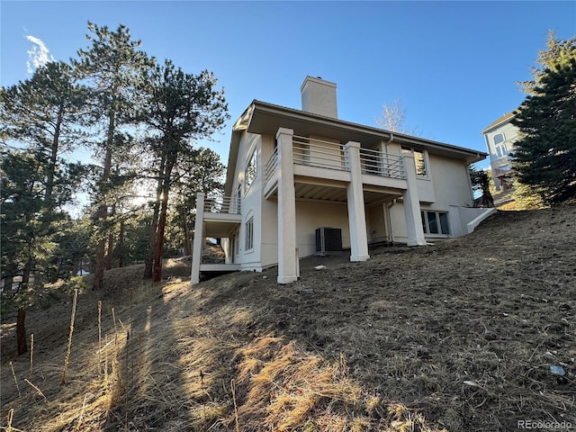 rear view of house featuring cooling unit and a balcony