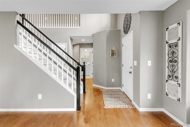 entrance foyer featuring a towering ceiling, baseboards, and wood finished floors