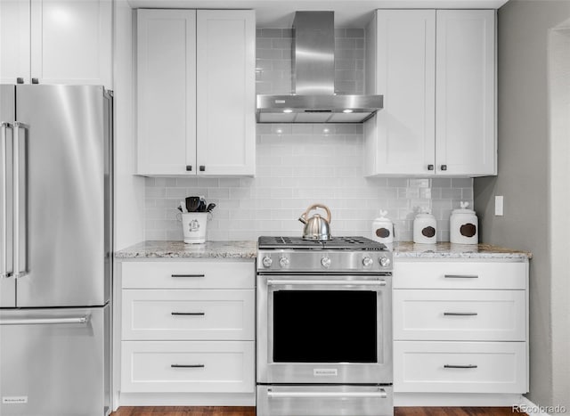 kitchen with stainless steel appliances, decorative backsplash, wall chimney exhaust hood, and light stone countertops