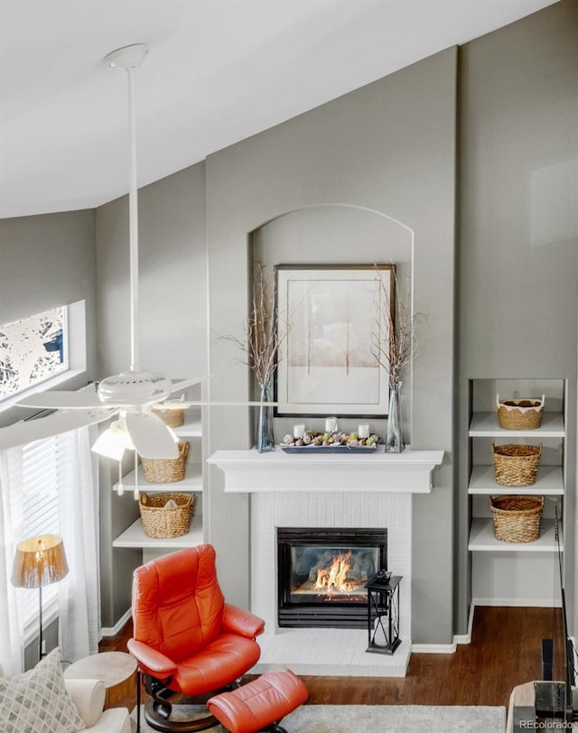 sitting room with a brick fireplace, wood finished floors, and baseboards