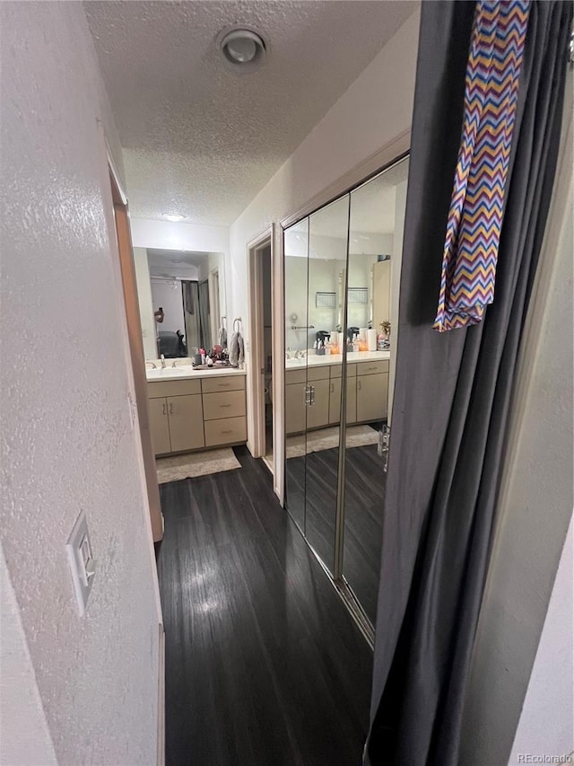 full bathroom with vanity, a textured ceiling, wood finished floors, and a textured wall