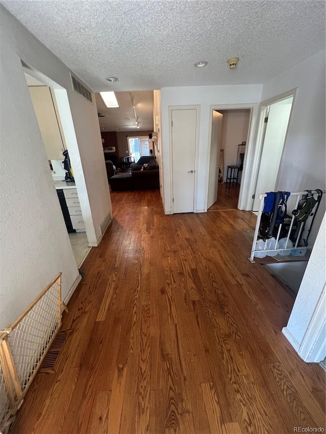 hallway with wood finished floors and a textured ceiling