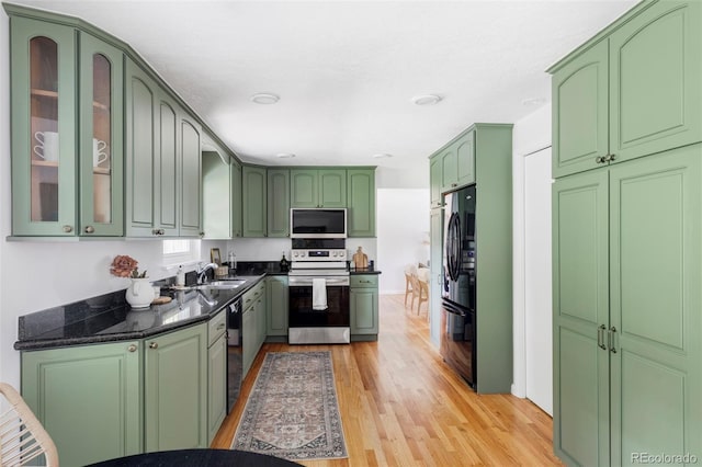 6982 Estes Dr, Arvada, CO 80004 - kitchen with black appliances, a sink, green cabinetry, light wood-style flooring, and glass insert cabinets