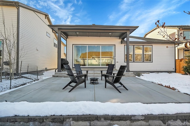 snow covered rear of property featuring an outdoor fire pit