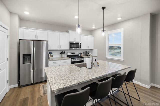 kitchen with white cabinets, appliances with stainless steel finishes, and a center island with sink