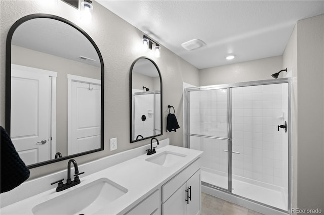 bathroom featuring vanity, a textured ceiling, a shower with shower door, and tile patterned flooring