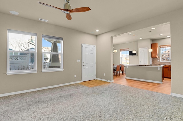 unfurnished living room featuring plenty of natural light, ceiling fan, and light wood-type flooring